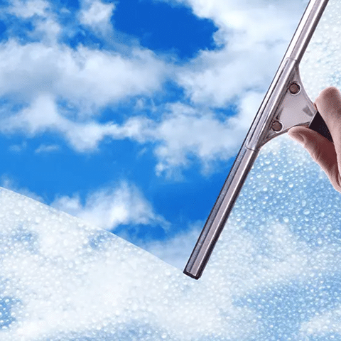 Window with clouds outside and a squeegee cleaning the glass